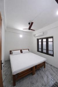 a white bed in a room with a ceiling fan at Enpathil Residency in Kollam