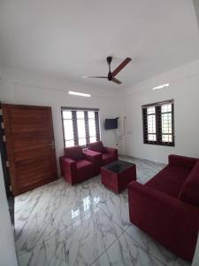 a living room with red couches and a ceiling fan at Enpathil Residency in Kollam