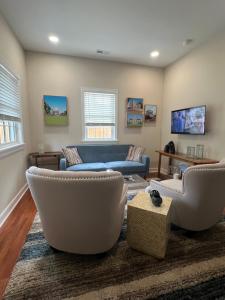 a living room with a blue couch and white chairs at Endicott Cottage in Richmond