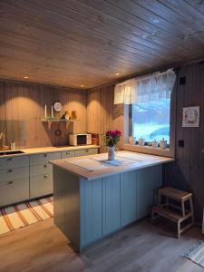 a kitchen with a island with a vase of flowers on it at Harteigen cabin Lofoten retreat in Vestvågøya