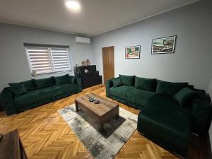 a living room with green couches and a coffee table at MONA app Apatin in Apatin