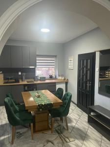 a kitchen with a wooden table and green chairs at MONA app Apatin in Apatin