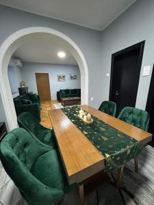 a living room with a wooden table and green chairs at MONA app Apatin in Apatin