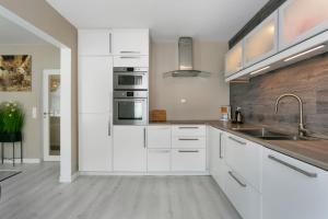 a kitchen with white cabinets and a sink at Centrum apartment 2 in Ålesund