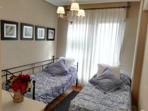 a bedroom with two beds and a vase of flowers at Apartamento Getxo Tranquility by I Love Norte in Getxo