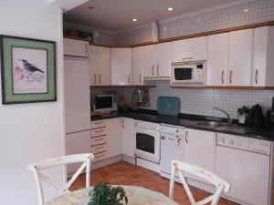 una cucina con armadi bianchi, tavolo e 2 sedie di Apartamento Getxo Tranquility by I Love Norte a Getxo