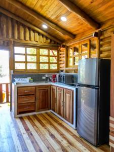 a kitchen with wooden cabinets and a stainless steel refrigerator at Cabañas Samara Buenavista in Sámara