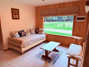 a living room with a couch and a window at Cabañas Agua y Campo in Osorno