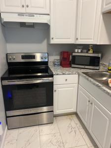 a kitchen with white cabinets and a stove and microwave at Trisuites 2 in New Orleans +5 photos