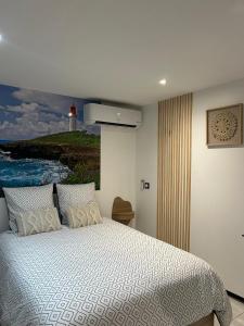 a bedroom with a bed with a painting of a lighthouse at Obonheur avec Jacuzzi in Le Gosier