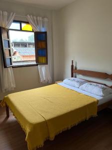 a bedroom with a yellow bed with a window at Hospedagem Casa de Déo in Domingos Martins