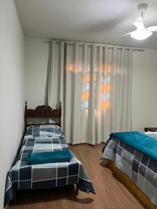 a bedroom with two beds and a window at Hospedagem Casa de Déo in Domingos Martins +2 photos