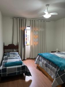 a bedroom with two beds and a ceiling fan at Hospedagem Casa de Déo in Domingos Martins