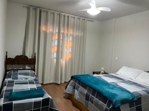 a bedroom with two beds and a ceiling fan at Hospedagem Casa de Déo in Domingos Martins
