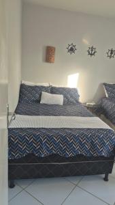 a bed with a blue and white comforter in a bedroom at Flat Mar doce lar in Conde +49 photos