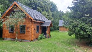 eine Holzhütte in einem grasbewachsenen Hof neben einem Haus in der Unterkunft Bez Planu in Zambski Stare + 11 Fotos