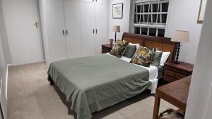 a bedroom with a bed and white cabinets at Hillcrest Cottage in Constantia