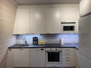 a kitchen with white cabinets and a sink at Idyllic Charm- with a moat! in Kangasala