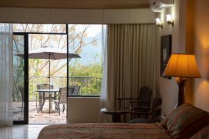 a hotel room with a bed and a view of a patio at Hotel Hacienda Cola del Caballo in Santiago