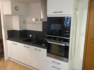 a kitchen with white cabinets and black appliances at La Parenthèse in Chalons en Champagne
