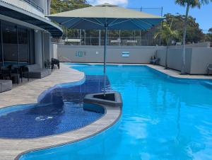 a swimming pool with an umbrella on a building at Landmark Resort 518 - Casablanca Penthouse 5th Floor in Nelson Bay