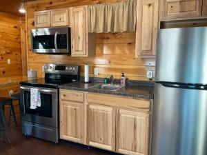 a kitchen with wooden cabinets and a stainless steel refrigerator at Blue Cozy Cottage in Oneida +6 photos