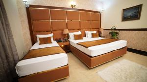 ein Schlafzimmer mit zwei Betten und einem großen Kopfteil in der Unterkunft Orchid Inn by WIH in Karatschi