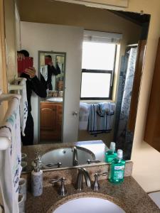 a woman taking a picture of a bathroom mirror at Stunning 2BD 2BA Ocean Front Condo Great View, AC in Wailuku