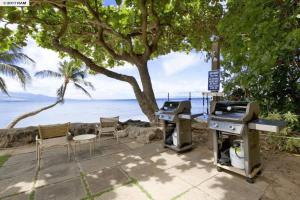 a patio with two bbq and a grill and chairs at Stunning 2BD 2BA Ocean Front Condo Great View, AC in Wailuku +3 photos