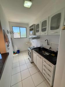 a white kitchen with a sink and a stove at Apartamento prático e aconchegante - 5 min do Centro in Catanduva
