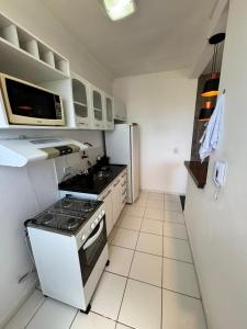 a small kitchen with a stove and a refrigerator at Apartamento prático e aconchegante - 5 min do Centro in Catanduva