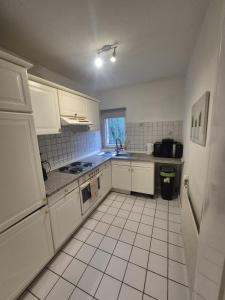a small kitchen with white cabinets and a sink at Süder11 - ApartB in Eddelak +4 photos