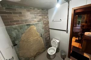 a bathroom with a brick wall and a toilet at Refugio da Serra - Cachoeira dos Bufalos in Pindamonhangaba