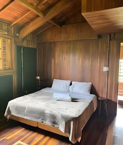 a bedroom with a large bed with wooden walls at Refugio da Serra - Cachoeira dos Bufalos in Pindamonhangaba
