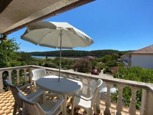 a table and chairs on a balcony with an umbrella at Apartment Solara in Kampor