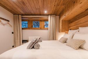 a bedroom with a large white bed with wooden ceilings at Luxury Chalet with Private Spa & Wellness Area in Megève