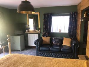 a black leather couch in a room with a window at Roundstone View in Bewdley