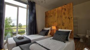 a bedroom with two beds and a large window at B&B Côté Moulin in Jayat