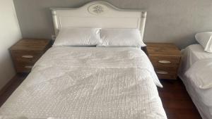 a bed with a white comforter and two night stands at Sürücü oteli in Milas