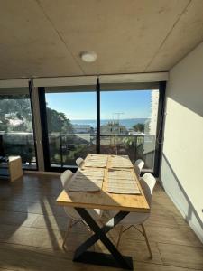 a wooden table and chairs in a room with large windows at Apartamento Piriapolis in Piriápolis