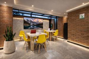 a restaurant with two tables and yellow chairs at Hotel Biba Life - Chia in Chía