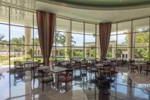 a dining room with tables and chairs and large windows at JOIA Paraiso by Iberostar - Adults Only All Inclusive Resort in Playa del Carmen