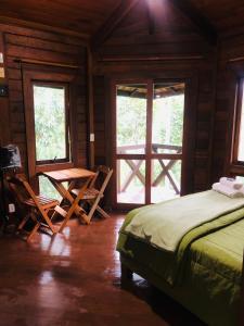 a bedroom with a bed and a table and windows at Refúgio eco Lodge in Nova Friburgo