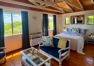 a bedroom with a bed and a chair and windows at Sunny studio in the sky in Brenton-on-Sea