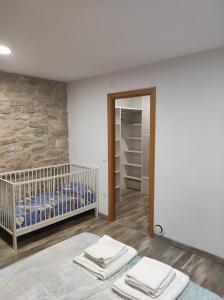 a bedroom with a crib and a stone wall at Casa Rural La Atalaya in Montarrón