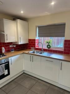 a kitchen with white cabinets and a sink and a window at Mill House in West Bromwich
