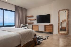 a bedroom with a bed and a tv and a mirror at Luxury 3BR Apartmen Tankah Beach plus Rooftop in Tulum