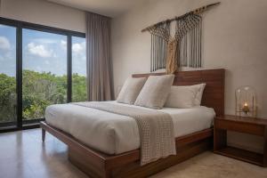 a bedroom with a bed and a large window at Luxury 3BR Apartmen Tankah Beach plus Rooftop in Tulum +25 photos