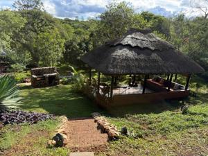a hut with a grass roof in a field at StoneWoodGrey in Harare
