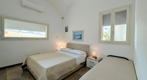 two beds in a white room with two windows at B&B Civico 11 in Veglie